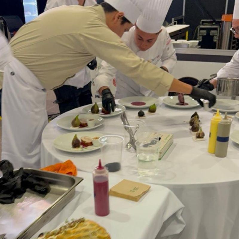 Chefs utilizando guantes de nitrilo negros durante emplatado en cocina profesional de alto nivel