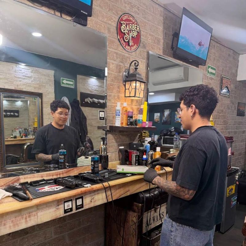 Barbero utilizando guantes de nitrilo negros en barbería, mostrando uso profesional en estética y cuidado personal